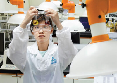 Formosa lab technician holding two beakers wearing formosa lab coat